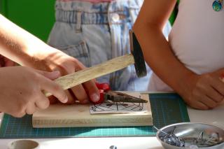 Kinder schlagen gemeinsam einen Nagel ein