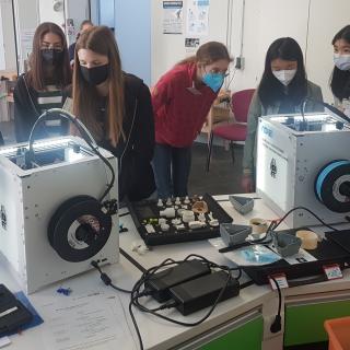 Die Mädchen verfolgen die schichtweise Entstehung ihrer maßgefertigten Bauteile im 3D-Drucker.