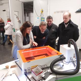 Teilnehmende im Technik-Workshop beobachten den Lasercutter bei der Arbeit